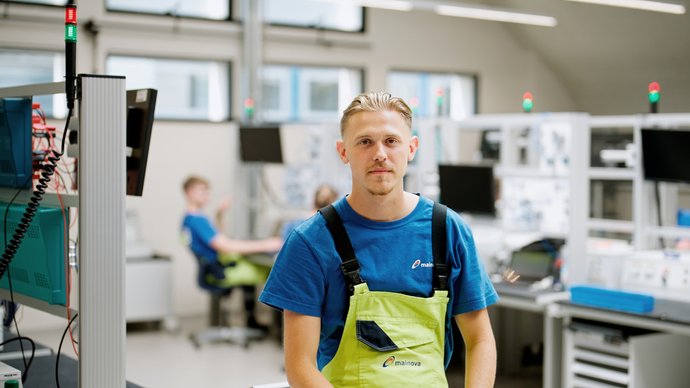 Sebastian Neudeck steht vor einer Werkbank und schaut in die Kamera