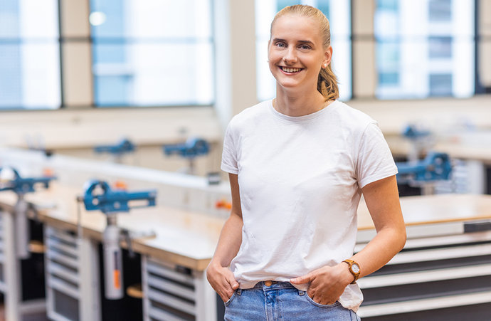 Clara Väth steht an einer Werkbank und schaut in die Kamera