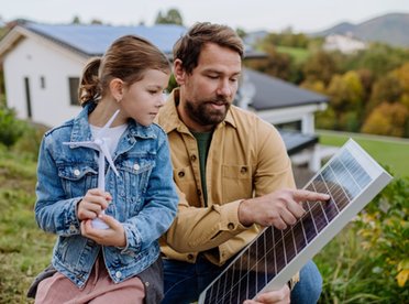 © www.istock.com/Halfpoint Mann zeigt einem Kind ein PV-Modul