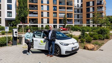 © Dennis Möbus Eine Frau und ein Mann stehen neben einem E-Auto, welches an eine Ladesäule angeschlossen ist