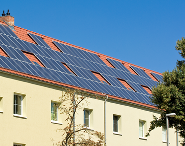 Ein Gebäude mit Solarpaneelen auf dem Dach, aufgenommen bei klarem, blauem Himmel.