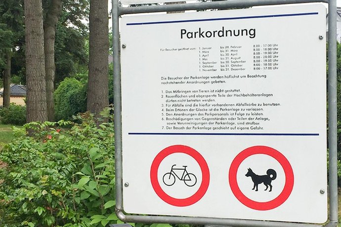 Ein weißes Schild mit Parkordnung und Öffnungszeiten.
