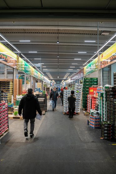 Obstkisten stehen rechts und links vom Gang, in dem die Mitarbeiter laufen
