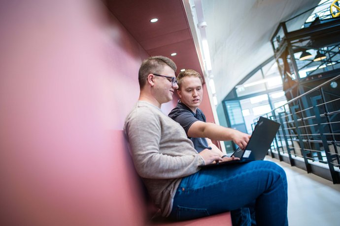 © Mainova/AndreFormer Ausbilder sitzt mit Notebook und bekommt vom Auszubildenden etwas am Monitor gezeigt