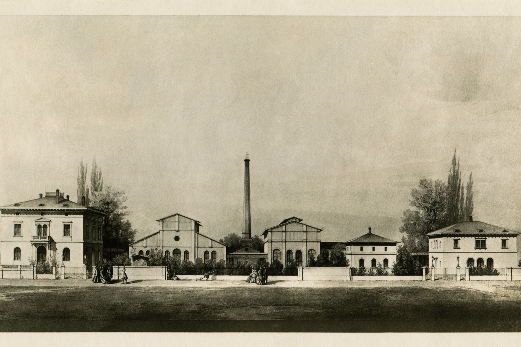 Das Bild zeigt eine historische Fabrikanlage mit mehreren Gebäuden und einem hohen Schornstein in der Mitte.