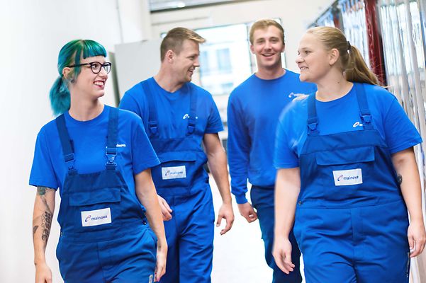 Gruppe Auszubildende laufen in Arbeitskleidung einen Gang entlang