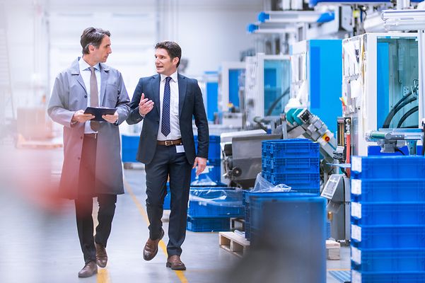 Zwei Geschäftsleute laufen durch Produktionshalle