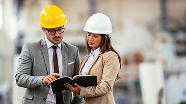 Geschäftsmann und Geschäftsfrau in Produktionshalle.