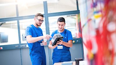 Zwei Auszubildende im Blaumann mit einem Elektromodul