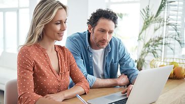 Mann und Frau schauen zu Hause gemeinsam auf Laptop