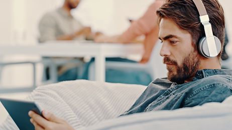 Ein Mann hält sein Tablet in der Hand und hört einen Podcast.