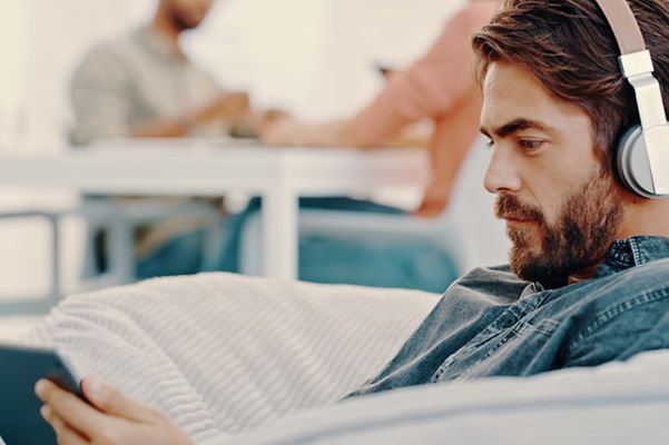 Ein Mann hält sein Tablet in der Hand und hört einen Podcast.