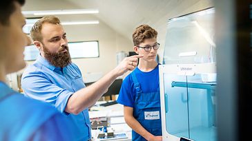 Ausbilder erklärt zwei Auszubildenden einen Schaltschrank