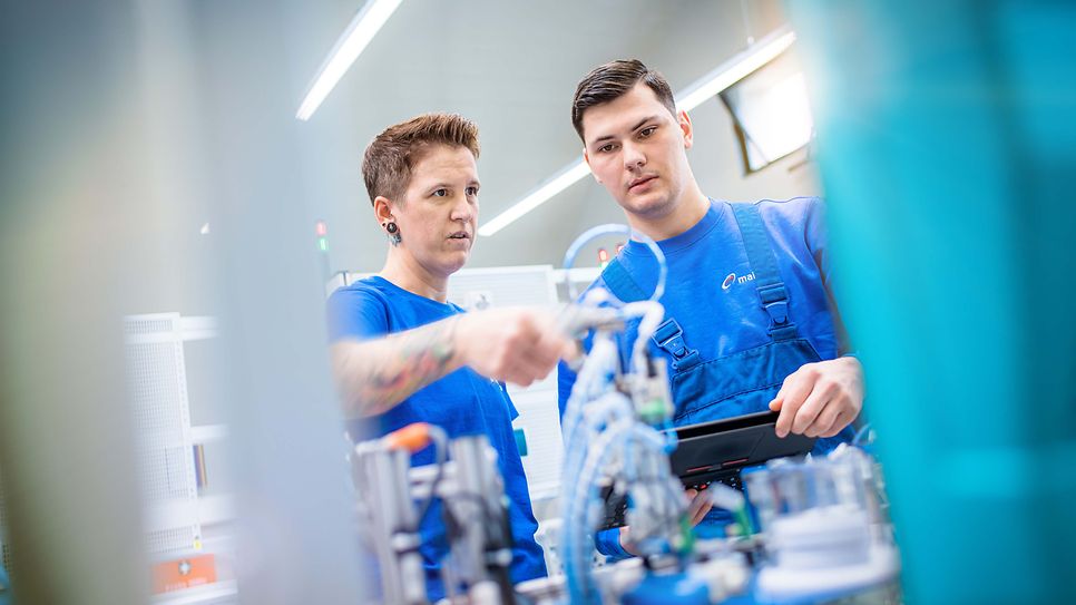 Ausbilder zeigt einem Auszubildenden eine Pneumatikinstallation