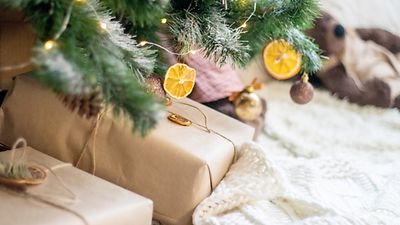 Geschenke unterm Weihnachtsbaum mit LED-Lichterkette und Baumschmuck