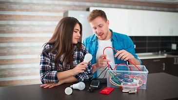 Junges Paar räumt Kabel und Elektrogeräte aus einer Kiste.