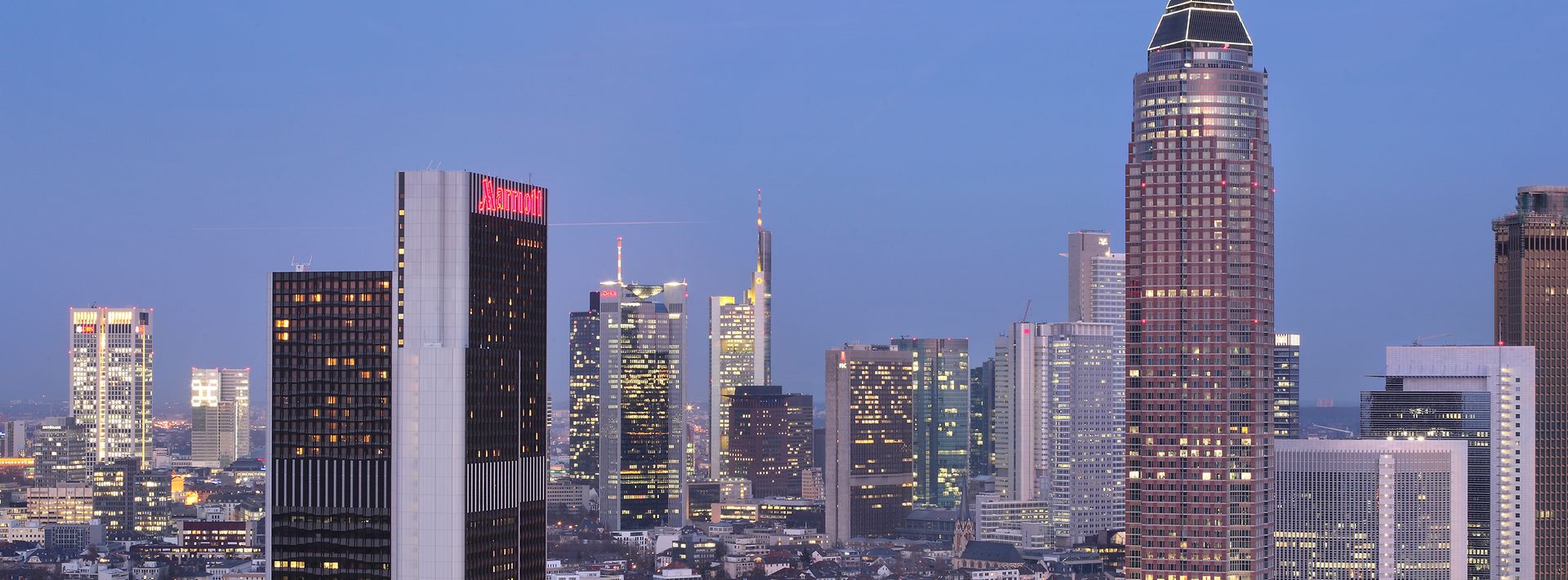 Skyline von Frankfurt bei Dämmerung mit mehreren Hochhäusern, darunter ein Marriott-Hotel.