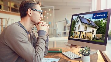 Ein Mann sitzt vor seinem Computer und nimmt an einem Online-Seminar teil.