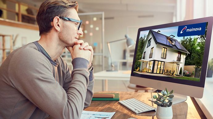 Ein Mann sitzt vor seinem Computer und nimmt an einem Online-Seminar teil.