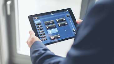 Mann hält Tablet mit App zur Lichtsteuerung