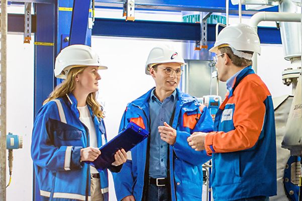 Gruppe mit Helm bespricht sich im Maschinenraum