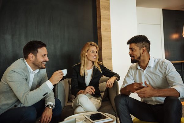 Drei Personen sitzen beisammen und unterhalten sich.