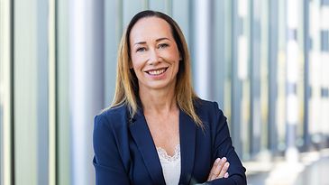 Tanja Richter steht vor einer Fensterreihe und schaut in die Kamera