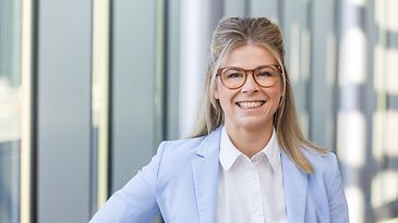 Dana Kröber steht vor einer Fensterreihe und schaut in die Kamera