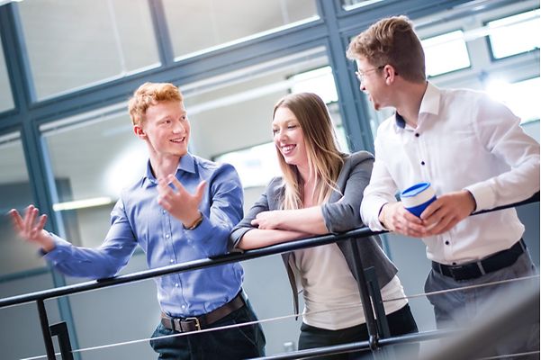 Drei junge Arbeitskollegen unterhalten sich miteinander.