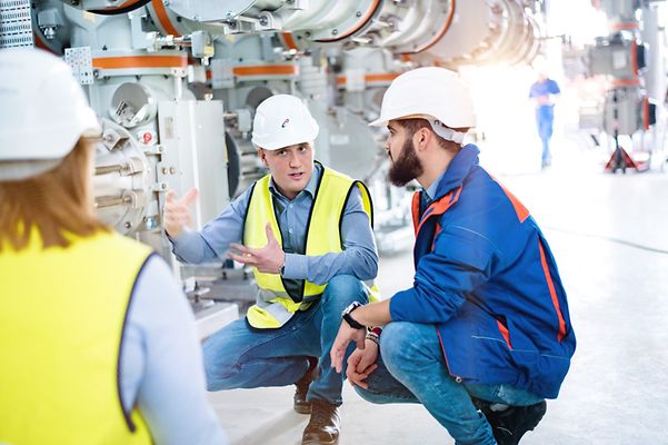 Drei Techniker vor einer Maschine besprechen sich.