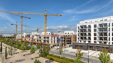 Siedlung mit Neubauten und Baukränen