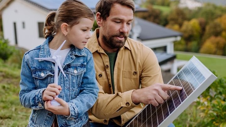 Mann zeigt einem Kind ein PV-Modul