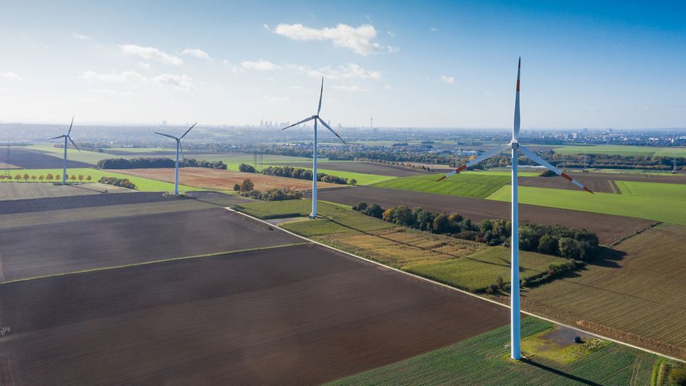 Windturbinen auf einem Feld, Stadtansicht Frankfurt in der Ferne.