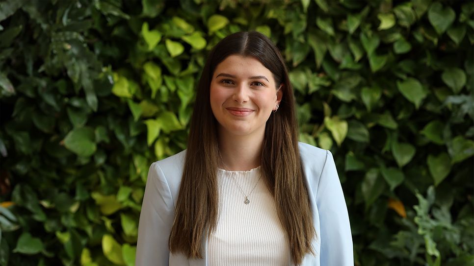 Bild von der Podcast Moderatorin Anna Hornung vor einer Pflanzenwand