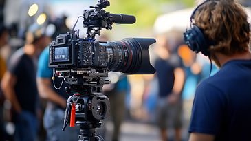 Mann sitzt hinter der Kamera und dreht eine Filmszene