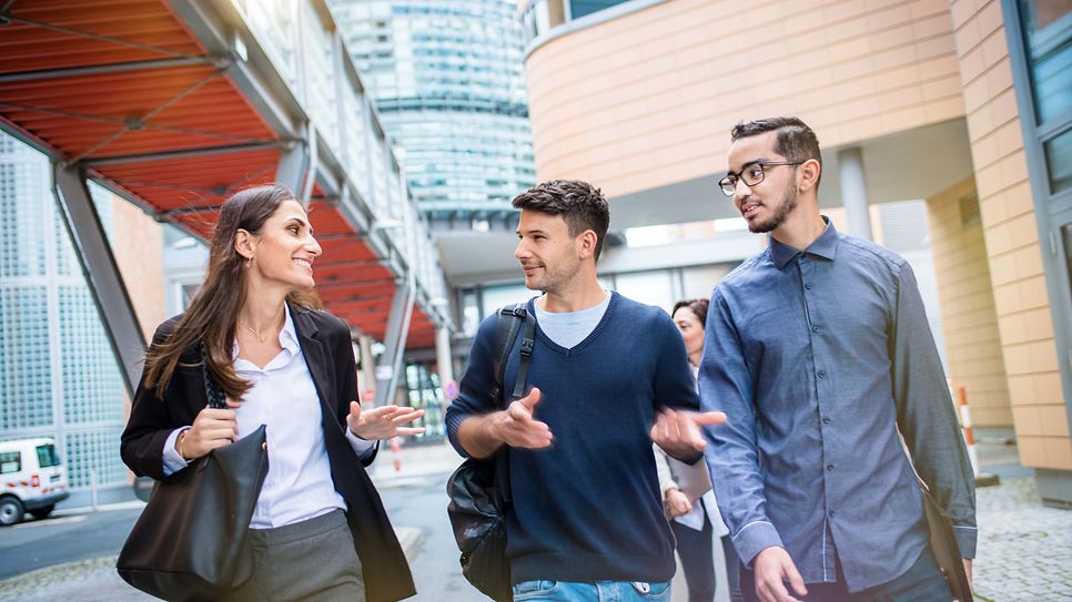 Drei junge Werkstudierende unterhalten sich beim Spaziergang auf dem Gelände der Mainova AG