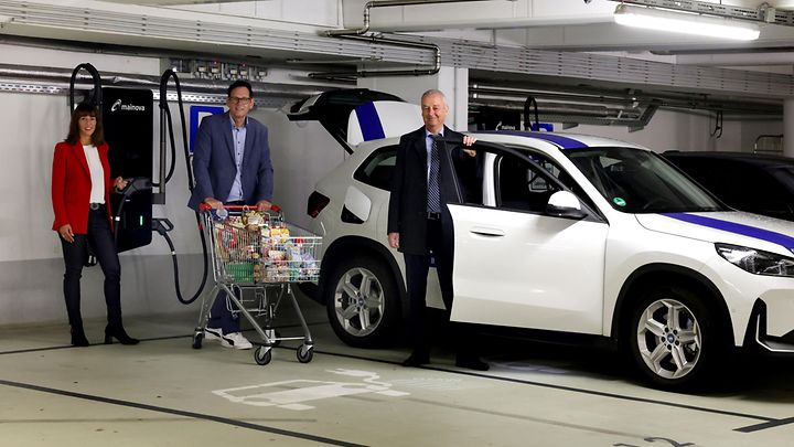 Drei Menschen in einer Tiefgarage vor einer Schnellladesäule