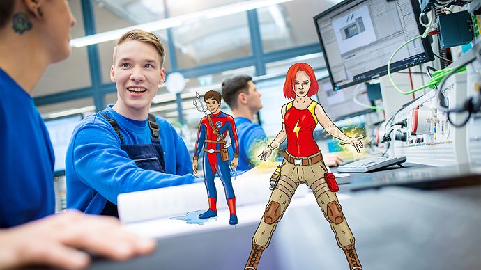 Zwei Auszubildende in Werkstatt, lächelnd, mit eingeblendeten Superhelden: eine Frau mit Blitzen und ein Mann im Anzug.