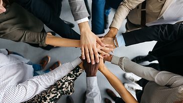 viele Hände, die übereinander liegen, um den Teamgedanken auszudrücken.