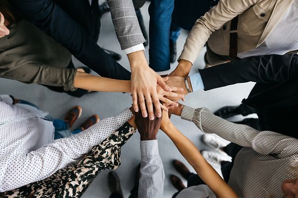 viele Hände, die übereinander liegen, um den Teamgedanken auszudrücken.