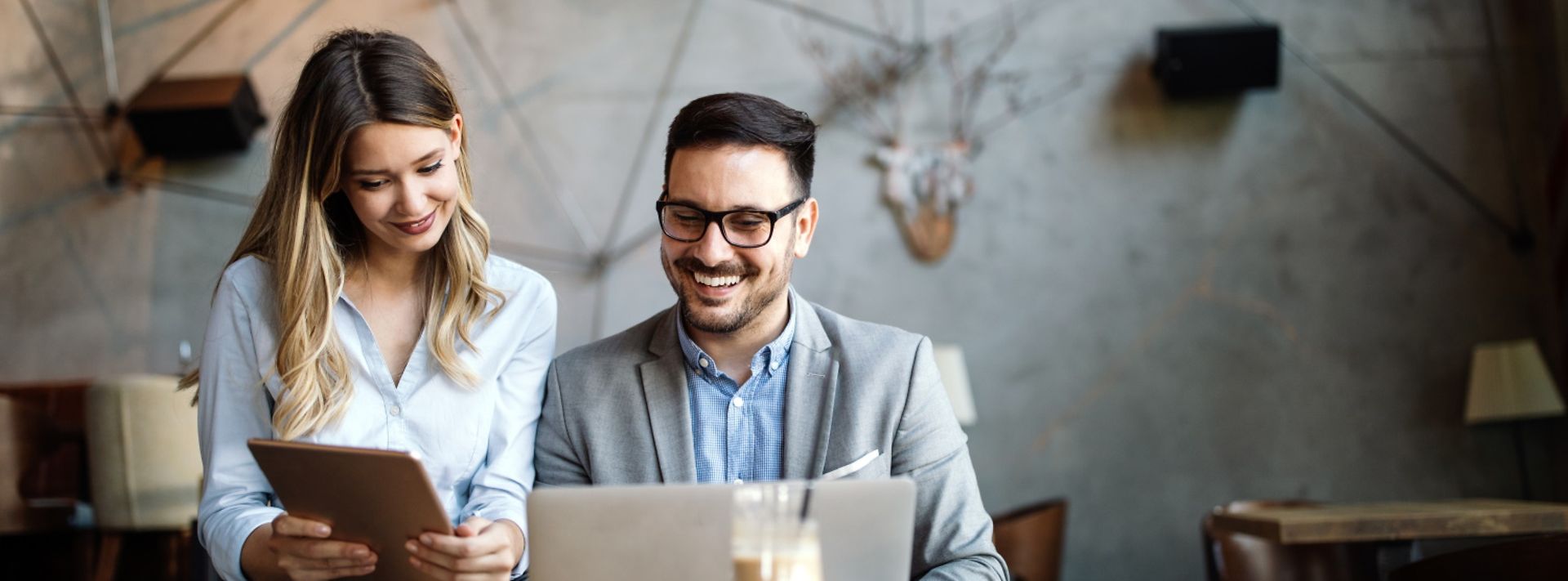© istockphoto.com/nd3000 Eine Frau und ein Mann beraten sich in einem Café und schauen gemeinsam auf ein Tablet.