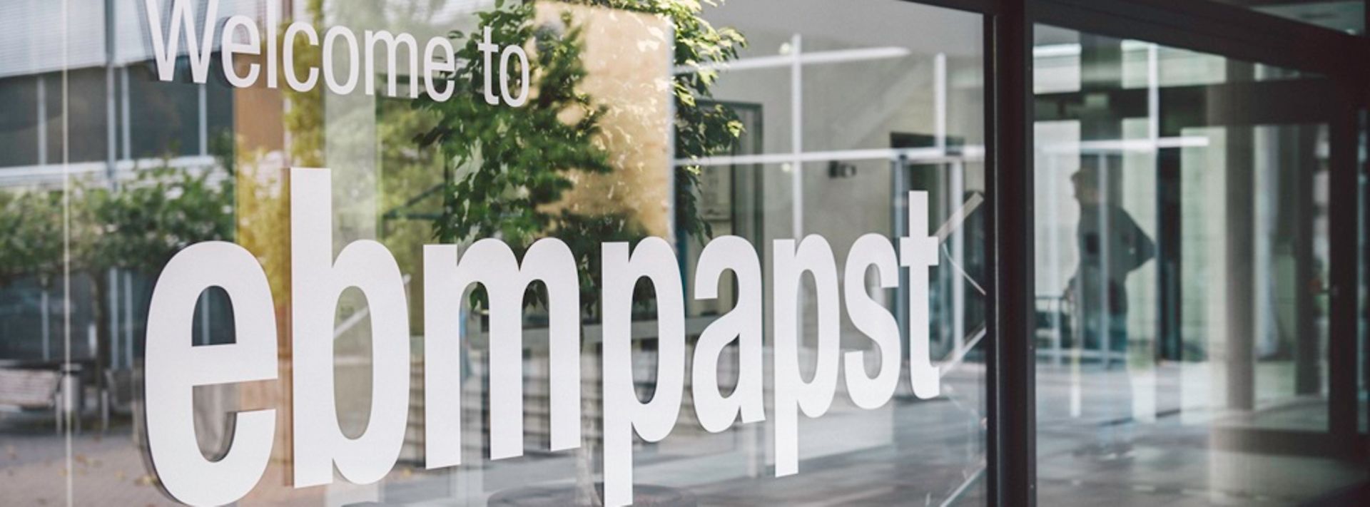 Weiße Aufschrift Welcome to ebmpapst an gläsener Front eines Firmengebäudes