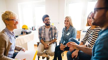 Eine Gruppe von Frauen und Männern sitzen im Kreis und reden
