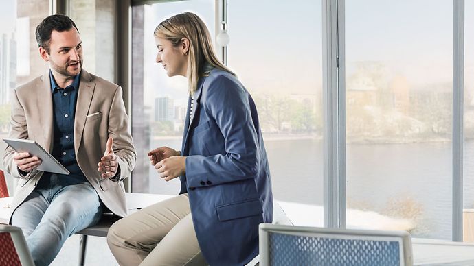 Geschäftsmeeting zwischen Mann und Frau im Büro vor der Skyline Frankfurt.
