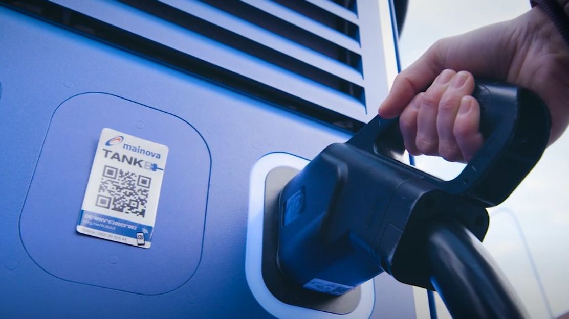 Eine Hand führt das Ladekabel zum Elektroauto 