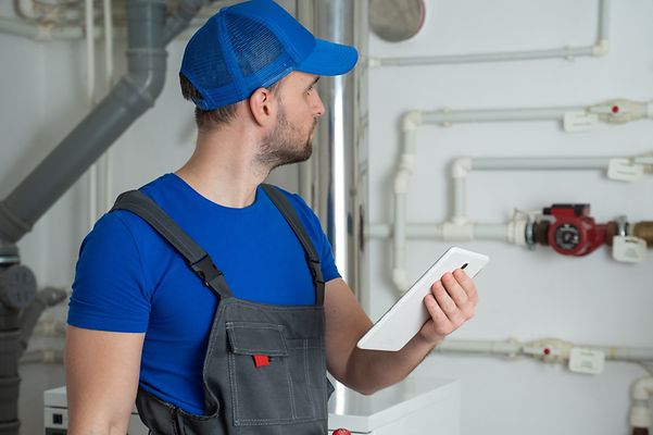 Heizungsmonteur steht im Heizungskeller vor einigen Rohrleitungen.