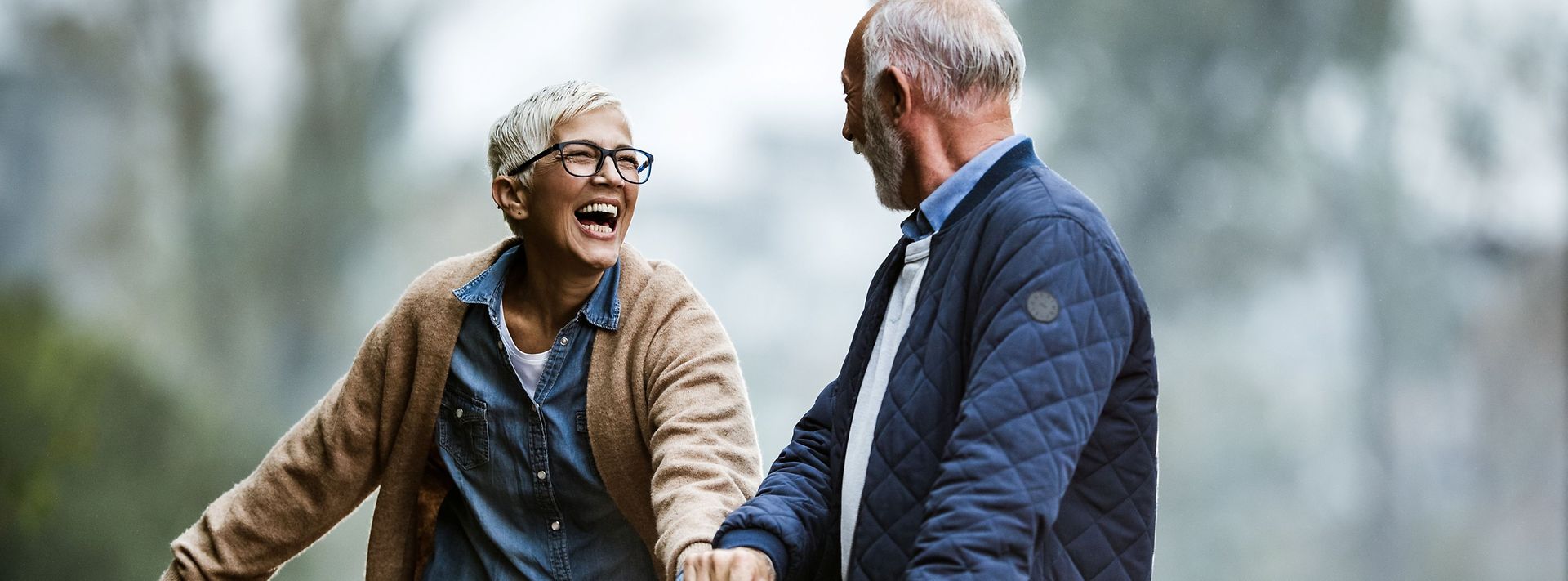 Älteres Ehepaar hält sich beim Spaziergang im Grünen an den Händen