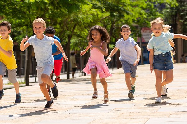 Kinder rennen glücklich auf einem Weg zwischen Bäumen