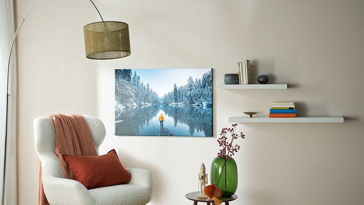 Sessel mit Lampe dahinter und kleinem Tisch und an der Wand ein Foto mit Schneelandschaft