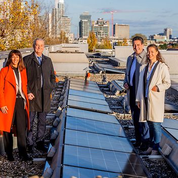 Vier Menschen stehen auf einem Dach mit Photovoltaikanlagen